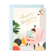 Boy sitting on chair blowing balloons with a cat on his lap birthday greeting card